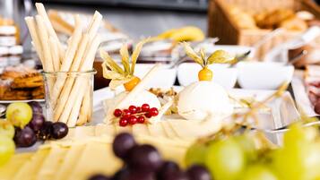 A buffet table with various food items including cheese, grapes, and breadsticks.
