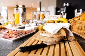 A breakfast buffet with various foods and a knife on a cutting board.