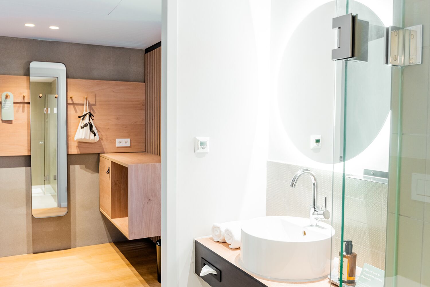 A modern bathroom with a large mirror, a round sink, and a glass shower enclosure.