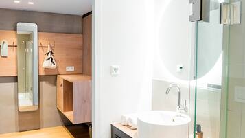 A modern bathroom with a large mirror, a round sink, and a glass shower enclosure.