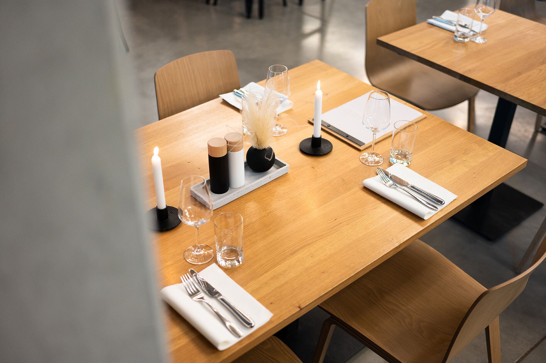 A dining table set with candles, glasses, and cutlery, suggesting a formal dining arrangement.