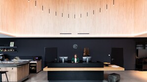 A modern reception desk with a wooden counter, a black desk, and a clock on the wall. - Coreum Hotel (Stockstadt am Rhein)