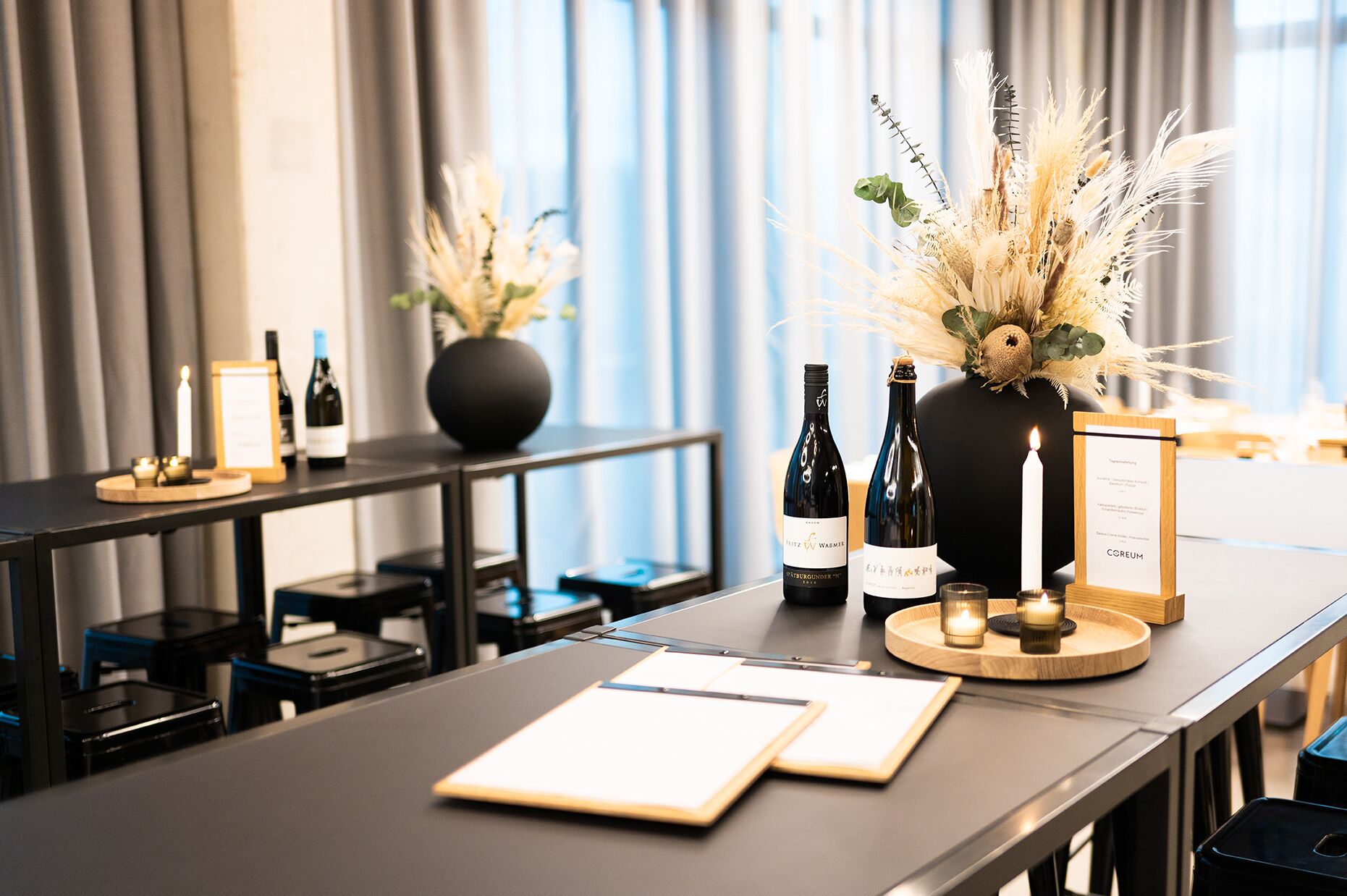 A hotel reception desk with a menu board, candles, and a vase of dried flowers.