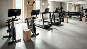A modern gym with treadmills, stationary bikes, and a rowing machine. - Coreum Hotel (Stockstadt am Rhein)