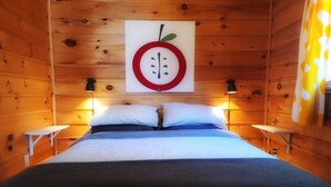 Une chambre confortable dans un chalet en bois, avec un lit, deux tables de chevet et une horloge fixée au mur.