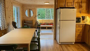 L’intérieur d’un chalet en bois comprend un coin repas, une cuisine et une grande fenêtre.