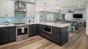 Une cuisine moderne avec des meubles de couleur sombre, des appareils électroménagers en acier inoxydable et un grand îlot central.