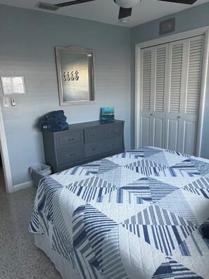 Une chambre à coucher comprenant un lit, une commode, un miroir et un ensemble de portes blanches.