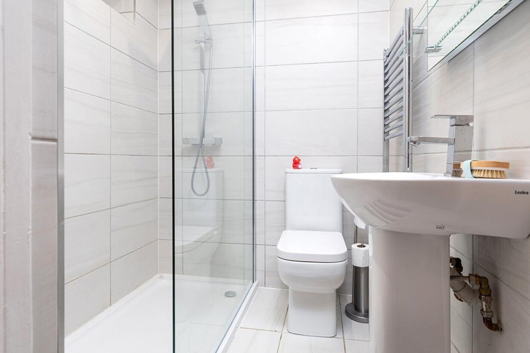 Ein modernes Badezimmer mit einer Duschkabine aus Glas, einer weißen Toilette und einem Standwaschbecken.