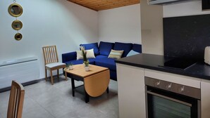 Una cocina compacta con horno integrado y un comedor con mesa y sillas de madera.