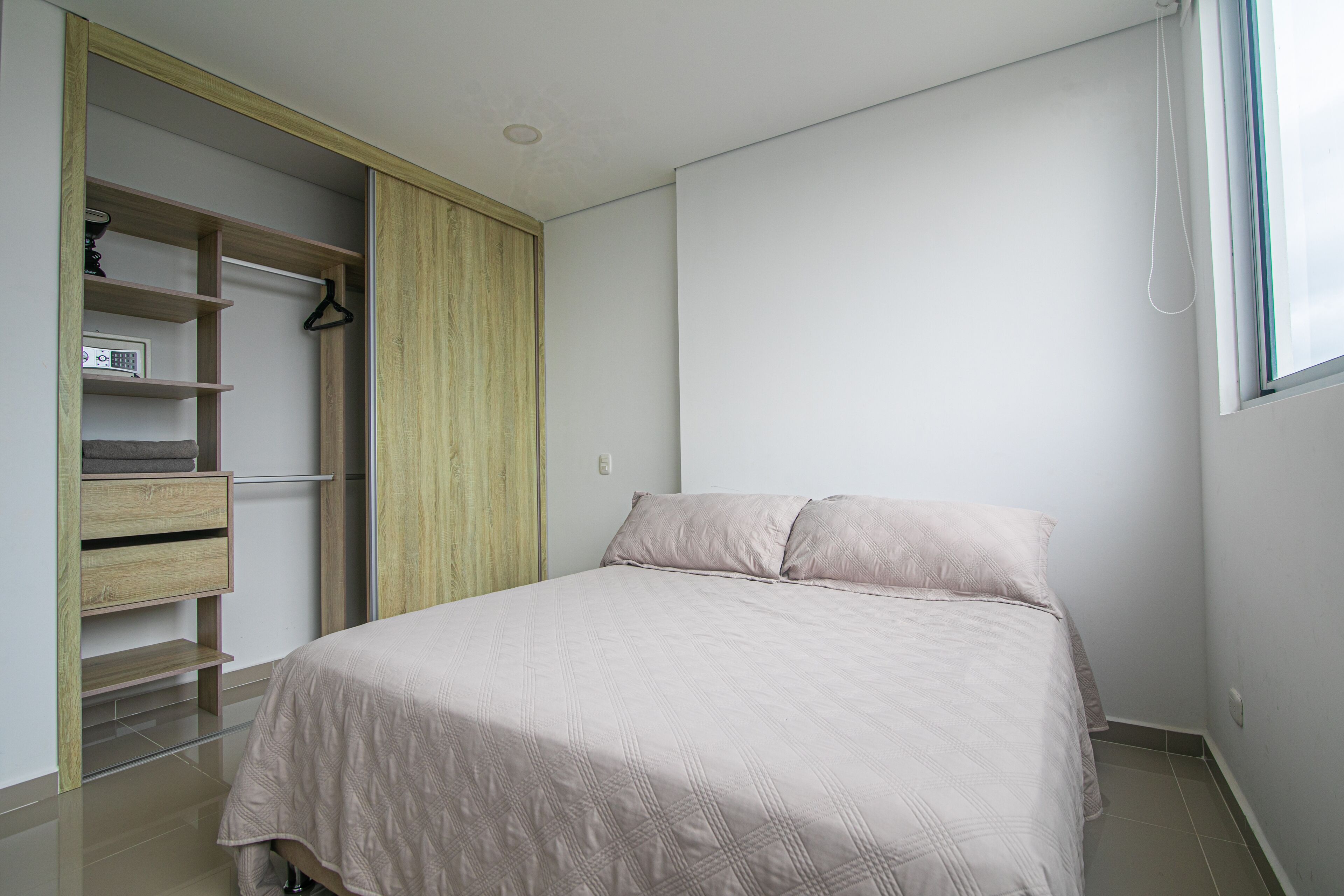 Un dormitorio con cama, armario y ventana.