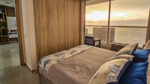 A bedroom with a large bed, a view of the city, and a sliding door closet. - LivingCartagena  (Cartagena)