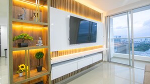A modern living room with a large flat-screen TV mounted on a wooden wall, a glass sliding door leading to a balcony, and a minimalist design with clean lines and a neutral color palette. - LivingCartagena  (Cartagena)