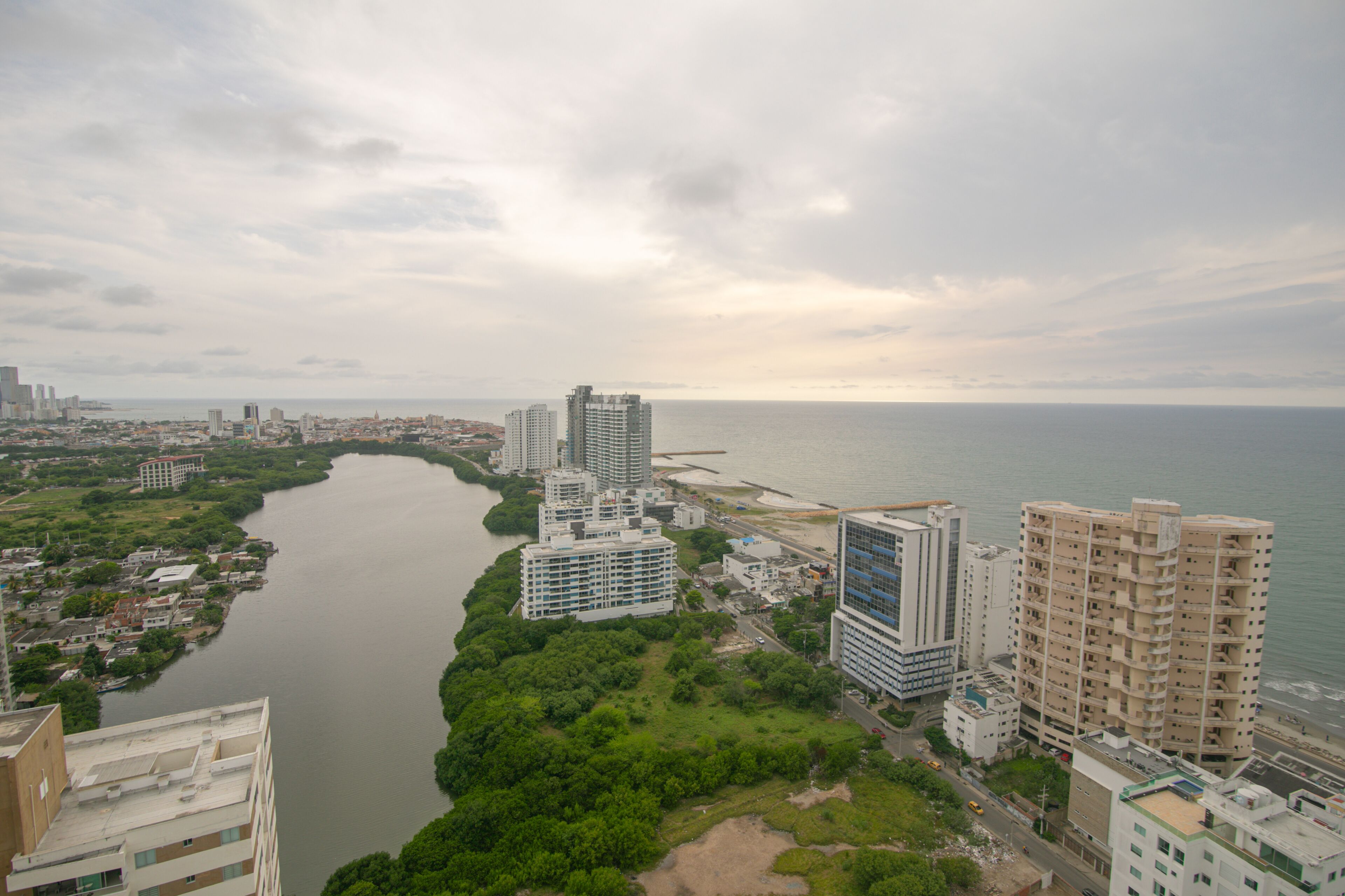Un paisaje urbano costero con rascacielos, un río y una playa.