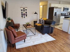 A living room with a sofa, armchair, coffee table, and a TV.
