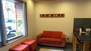 Un espai vital reduït amb un sofà, otomana i una petita zona de cuina.