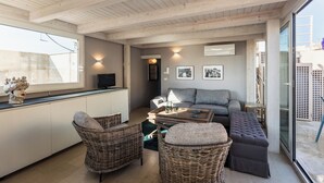 Ein gemütlicher Wohnbereich mit Korbmöbeln, einem grauen Sofa und einem Couchtisch.