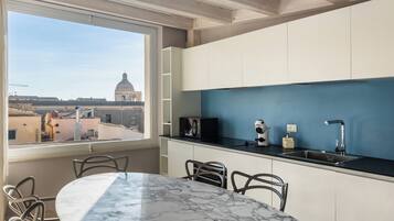 Una cucina moderna con vista su una cupola e degli edifici, un tavolo in marmo e sedie in metallo.