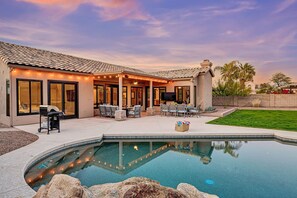 A house with a swimming pool, patio furniture, and a barbecue area.