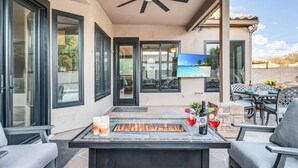 Une terrasse dotée d’un foyer extérieur, de sièges et d’un téléviseur.