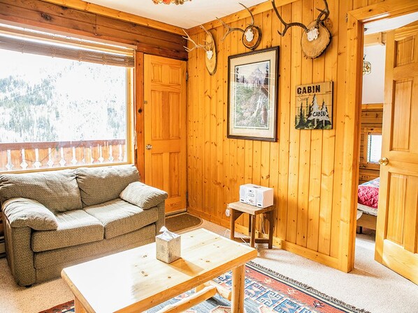 A cabin interior with wooden walls, a sofa, a table, a framed picture, and a sign that reads "CABIN."