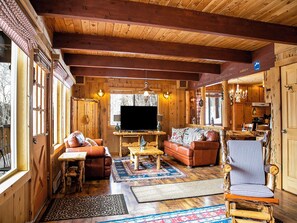 Interior acogedor de una cabaña de madera con sala de estar, un sofá, una mesa de centro y un televisor.