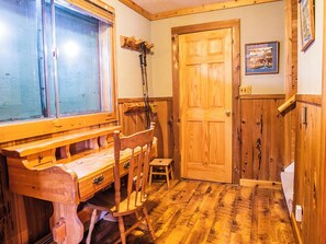 A wooden interior with a desk, chairs, a door, and a window.