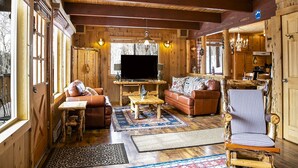 L’intérieur d’un chalet en bois chaleureux et accueillant, avec un salon comprenant un canapé, une table basse et un téléviseur.