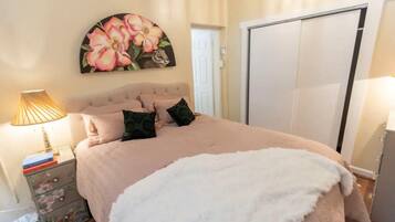 A bedroom with a bed, a nightstand, a dresser, a painting, and a wardrobe.