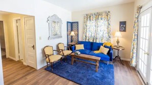 A living room with a blue sofa, two armchairs, a coffee table, and a patterned curtain.