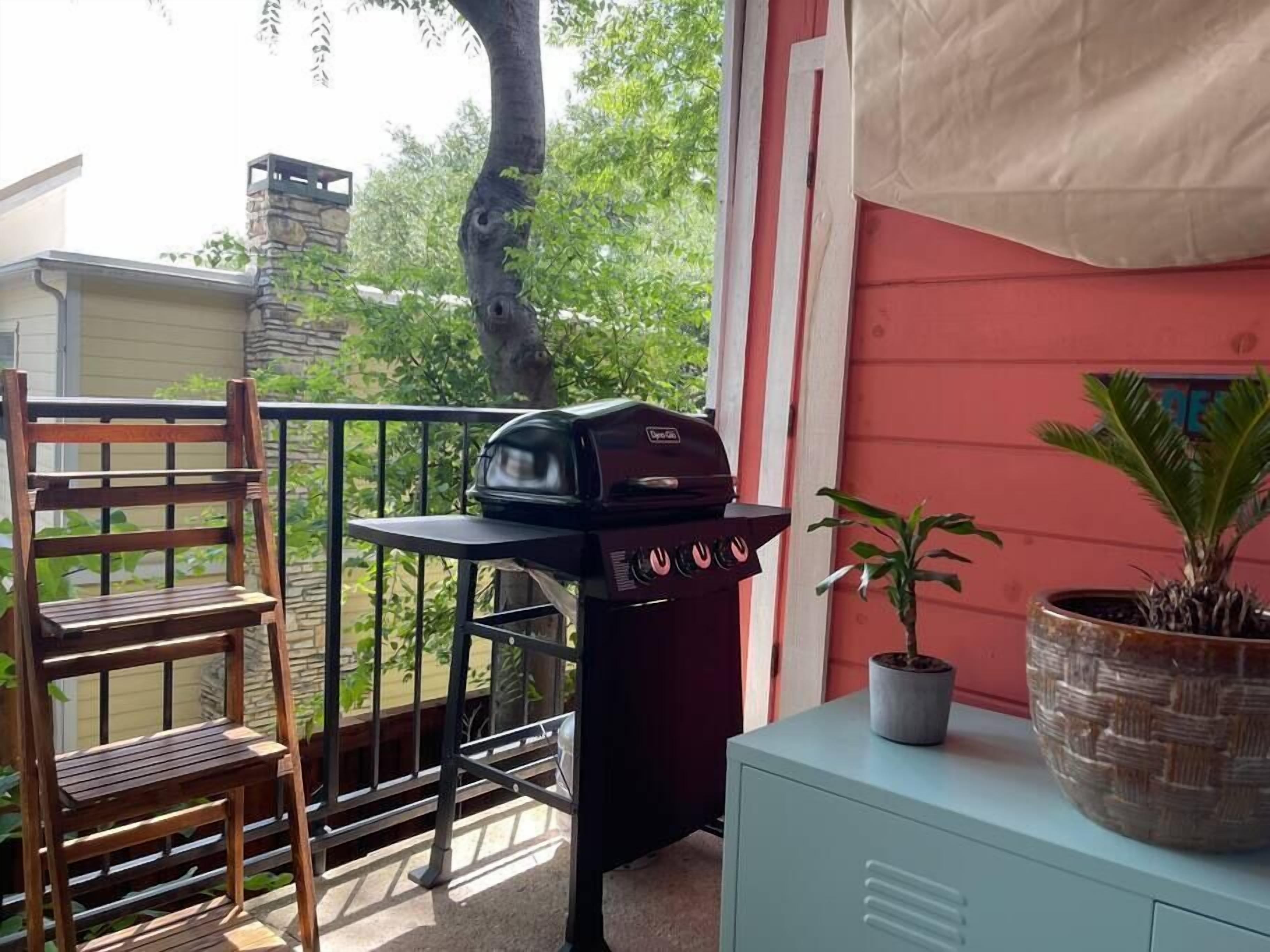A balcony with a grill, a chair, a potted plant, and a cabinet.