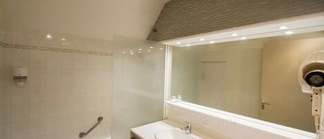 A modern bathroom with a glass shower enclosure, a white sink, and a large mirror.