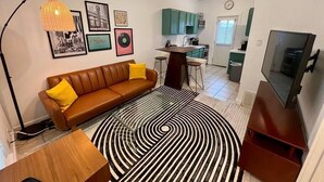 Una sala de estar moderna con un sofá de cuero marrón, un tapete a rayas blancas y negras y un ventilador de techo.