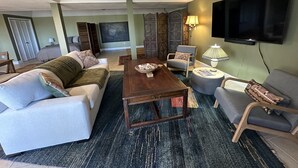 Una sala de estar moderna con un sofá, sillones, una mesa de centro y un televisor.