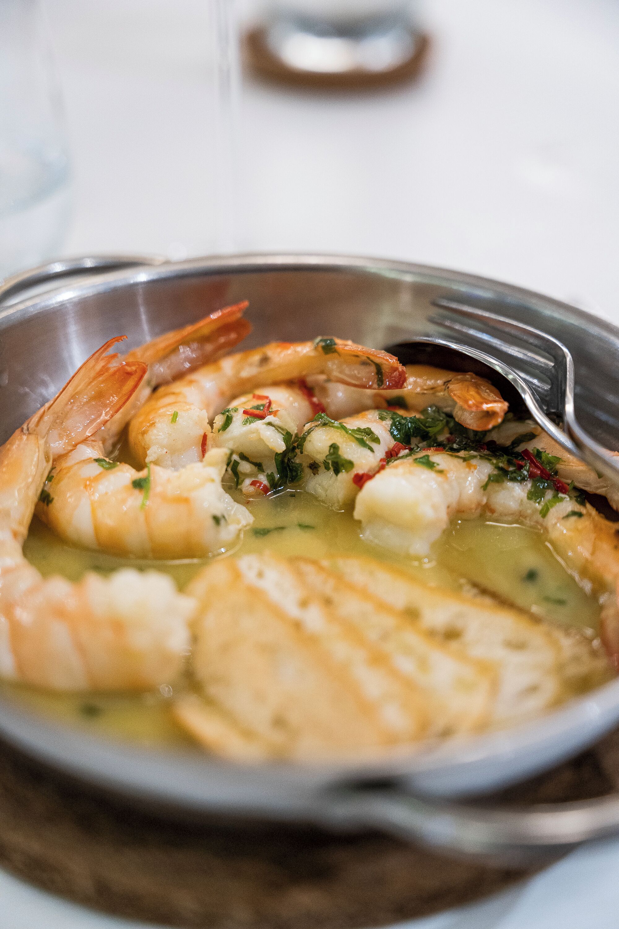 Un bol de crevettes cuites, agrémentées d’herbes et servies avec une sauce.