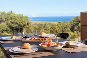 Ein Tisch ist für eine Mahlzeit gedeckt, mit einem schönen Blick auf das Meer und Bäume im Hintergrund.