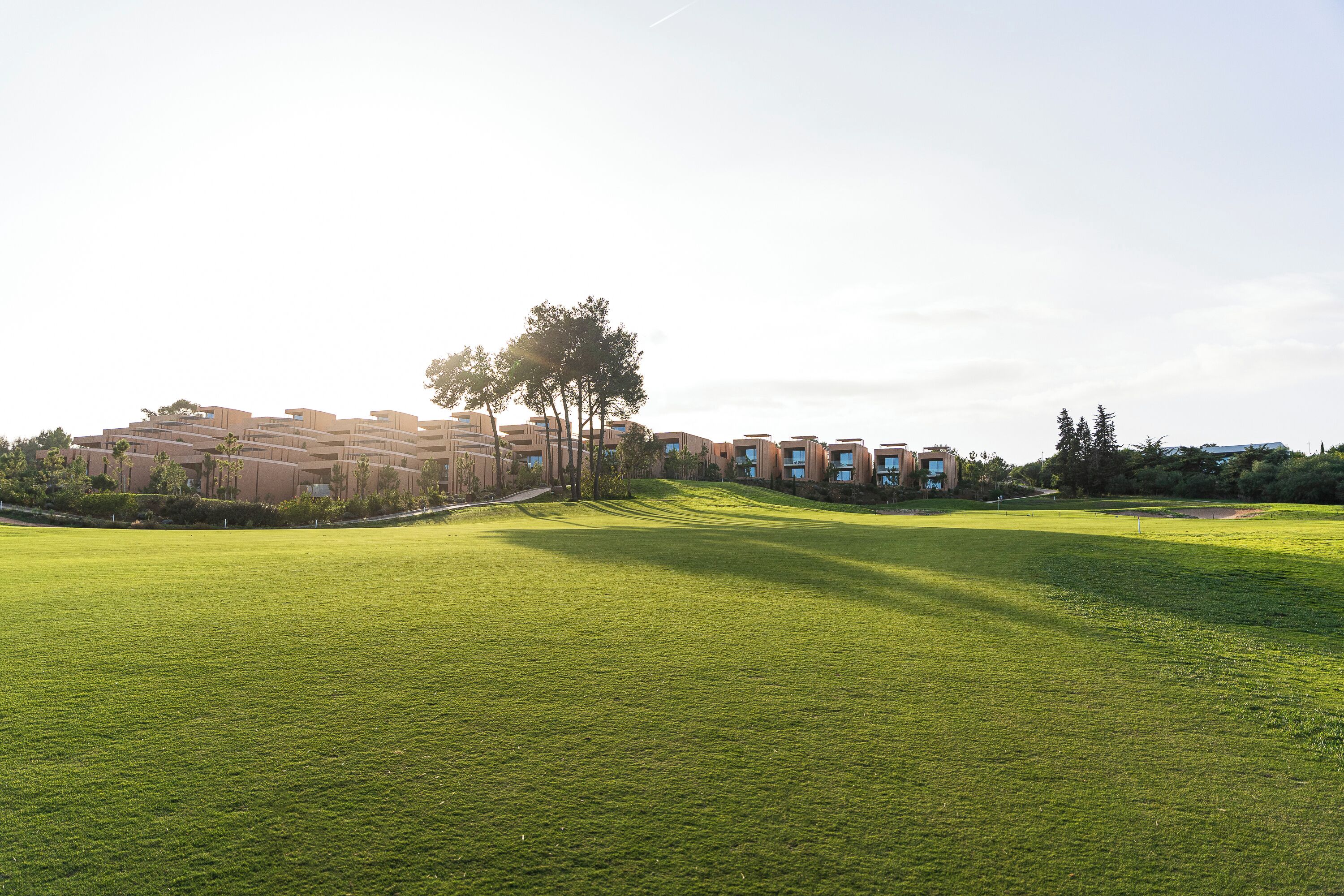 Camp de golf amb un complex arquitectònic modern al fons.