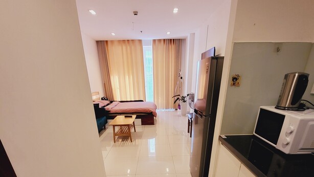 Corredor de hotel com cozinha, cama e mesa de jantar.