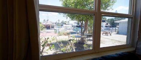 A window with a view of a marina, outdoor seating, and a tree.