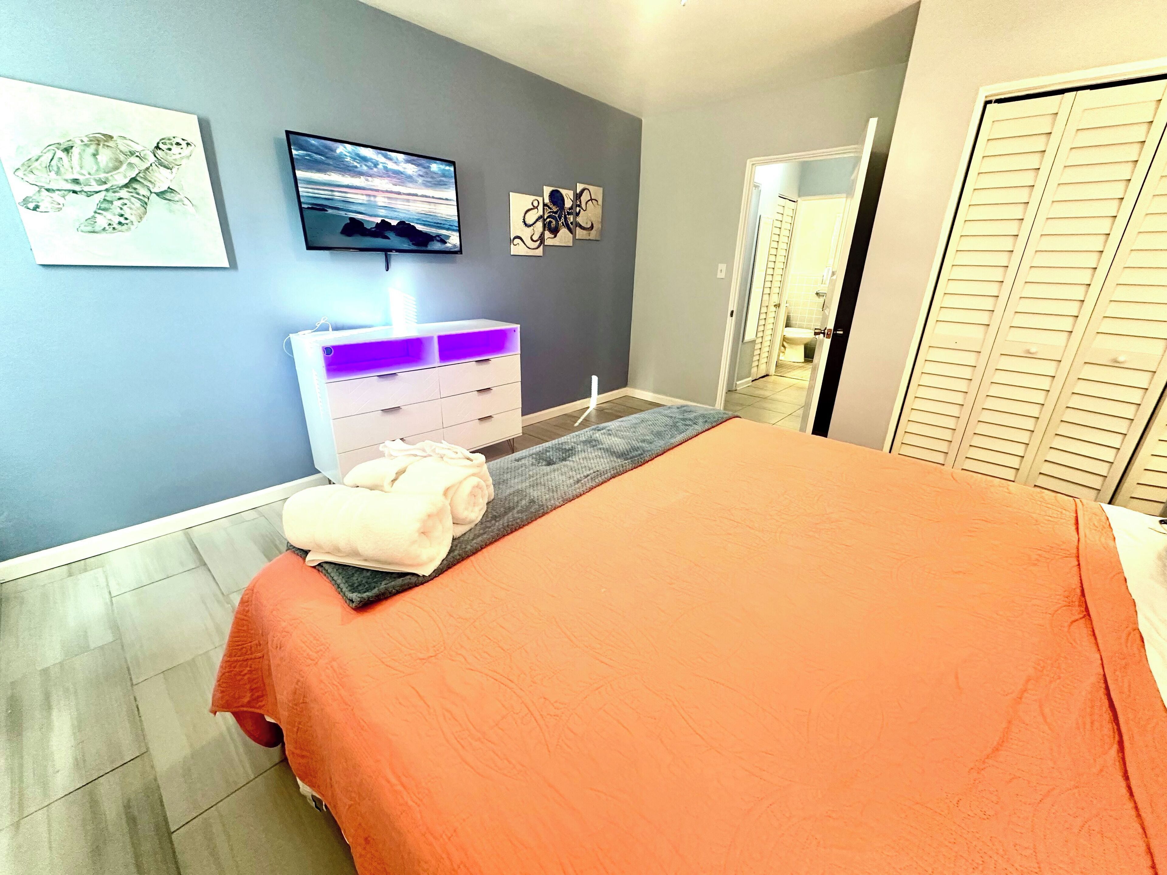 A bedroom with a bed, a dresser, and artwork on the wall.