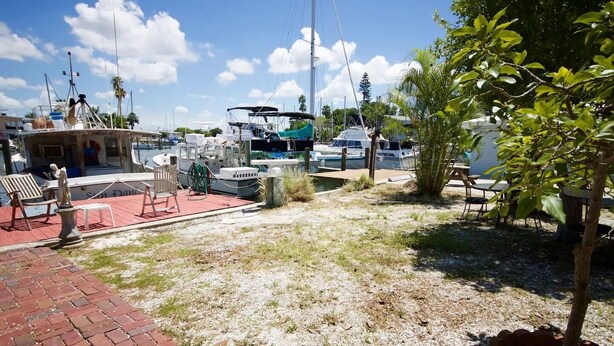 Un puerto deportivo con barcos amarrados, una estatua y mesas al aire libre.