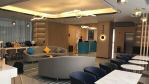 En moderne hotellobby med reception, siddeområde og bar.