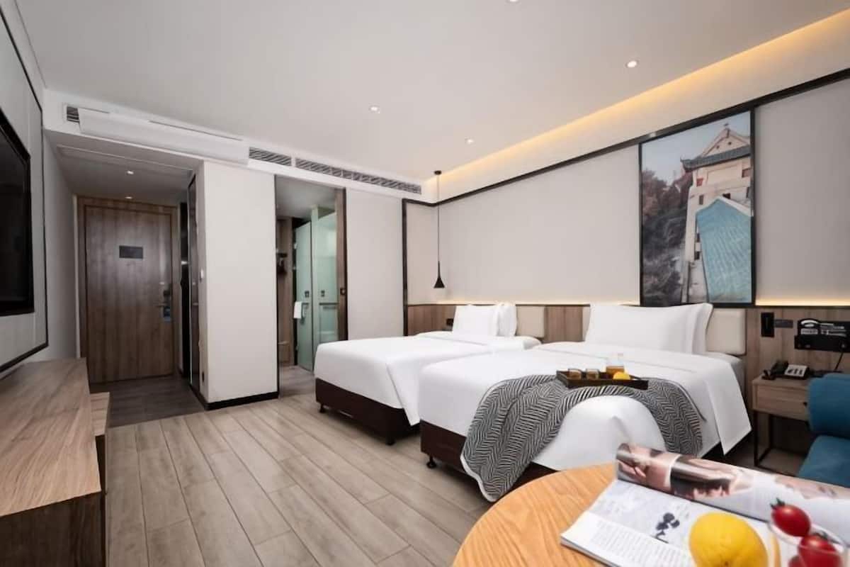 Een hotelkamer met twee bedden, een bureau, een stoel, een tafel en een tijdschrift.