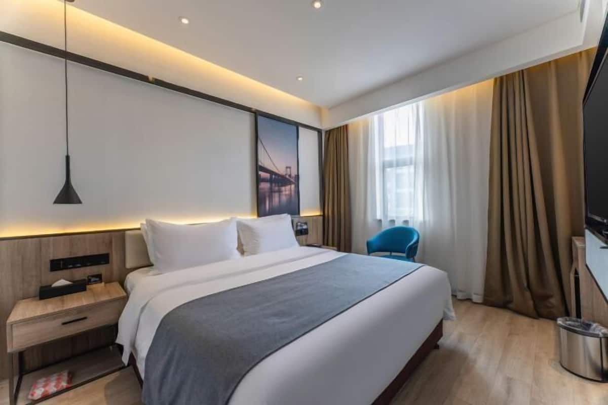 Een moderne hotelkamer met een groot bed, een bureau, een stoel en een televisie.