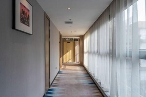 Un couloir avec un tapis à motifs, un tableau encadré au mur et une porte au fond.