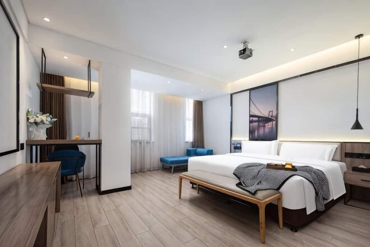 Een moderne hotelkamer met een bed, bureau en zithoek.