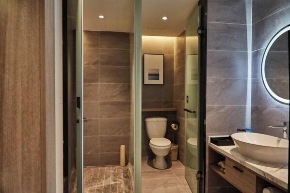 A modern bathroom with a large sink, toilet, and shower area.