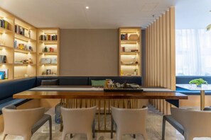 Un espace de salle à manger moderne avec une longue table, des chaises et des étagères.