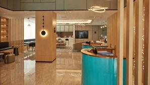 A modern hotel lobby with a reception desk, seating area, and a TV screen. - Wuhan Bilang Jia Hotel (Optics Valley Financial Gangbei Subway Station) (Wuhan)