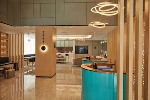 A modern hotel lobby with a reception desk, seating area, and a TV screen. - Wuhan Bilang Jia Hotel (Optics Valley Financial Gangbei Subway Station) (Wuhan)